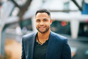 Outdoor portrait of handsome afro american man, city landscape on background